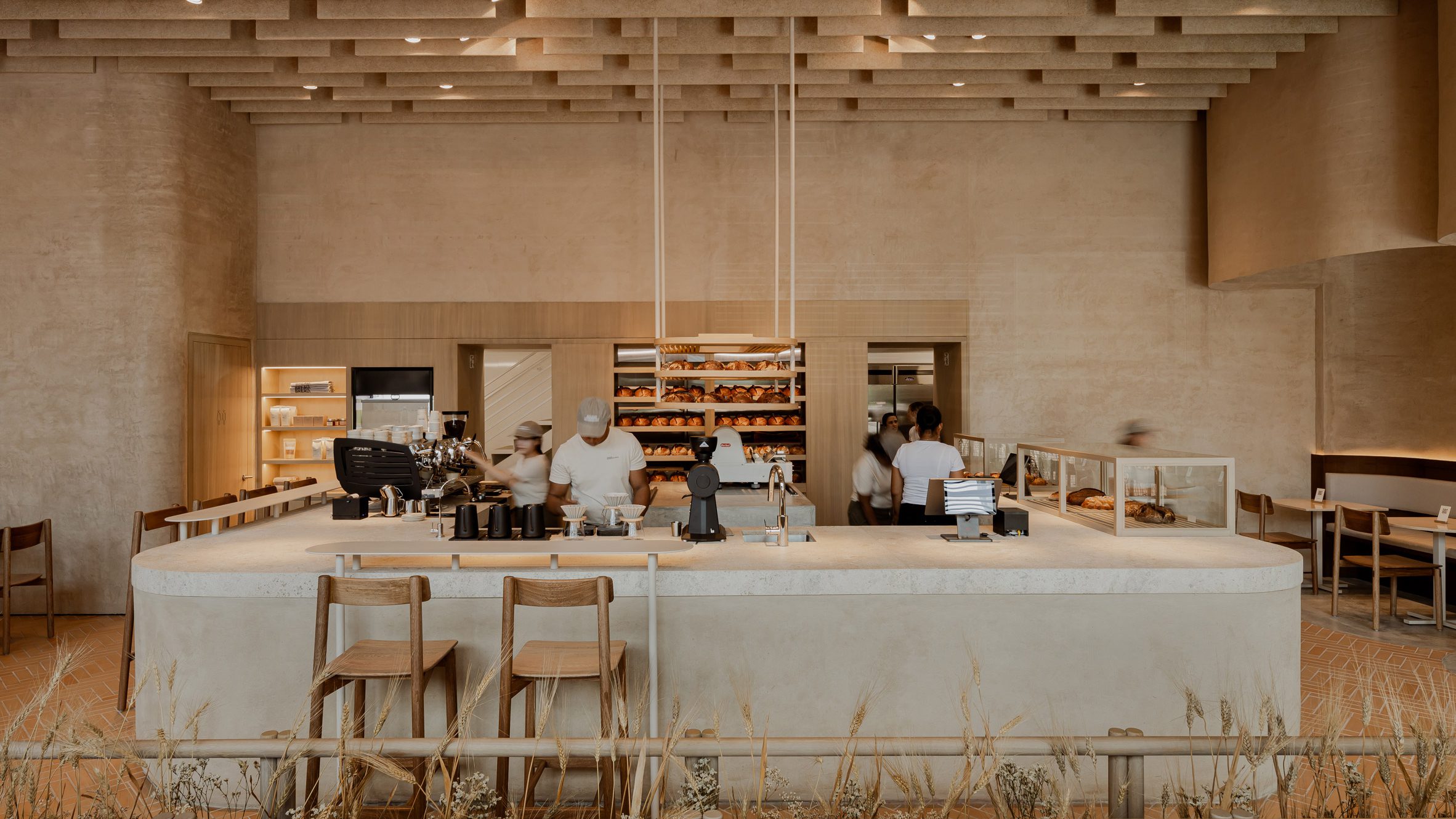 La panadería se articula alrededor de un mostrador en forma de U construido con tierra compactada, una técnica ancestral reinterpretada con elegancia contemporánea.