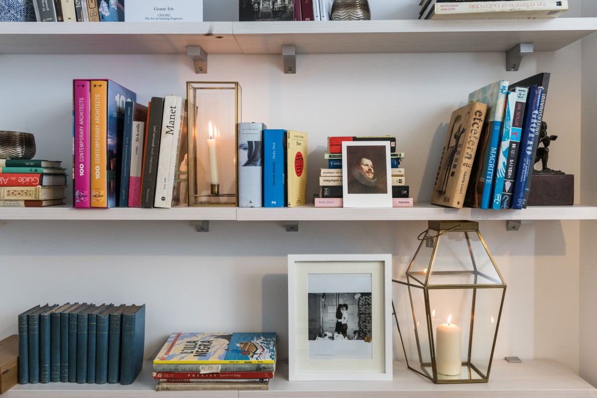 Baldas blancas blancas con libros y detalles decorativos como marcos de fotos y jarrones