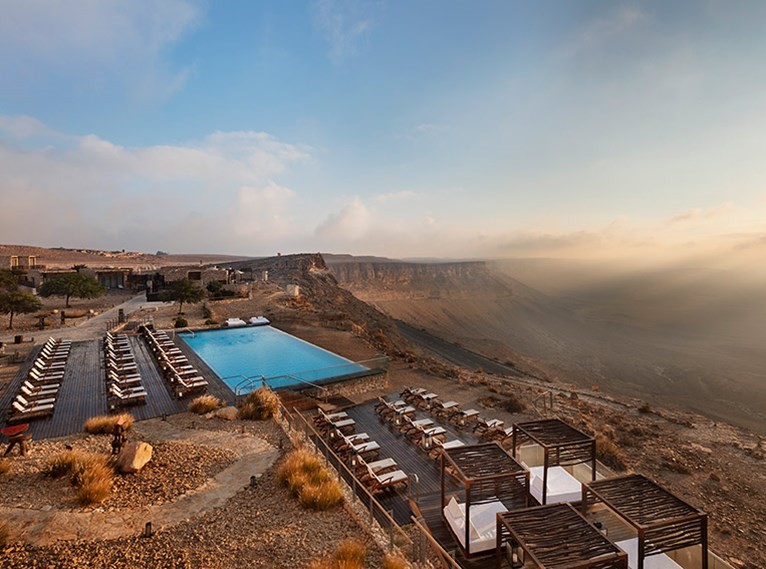 La piscina, acompañada por tumbonas y camas