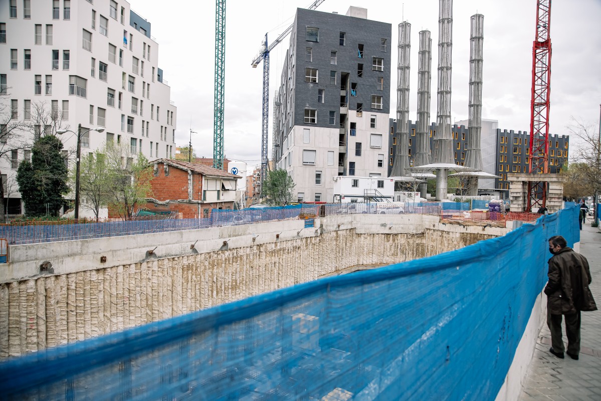 Un hombre mira una obra, en construcción, parada y sin trabajadores, por falta de suministros como el hormigón, en Vallecas