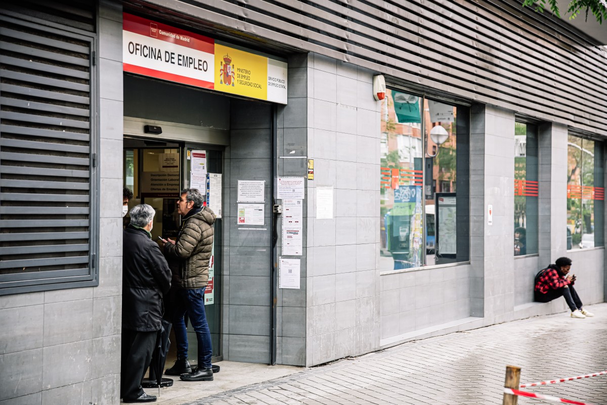 Varias personas en la entrada de una oficina de empleo