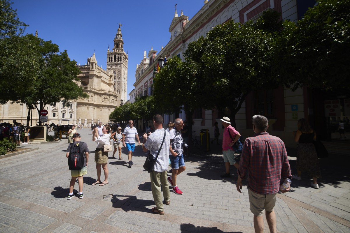 Varios turistas pasean por la plaza del Triunfo en Sevilla