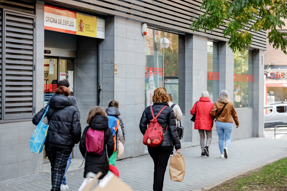 Archivo - Varias personas pasan frente a una oficina de empleo