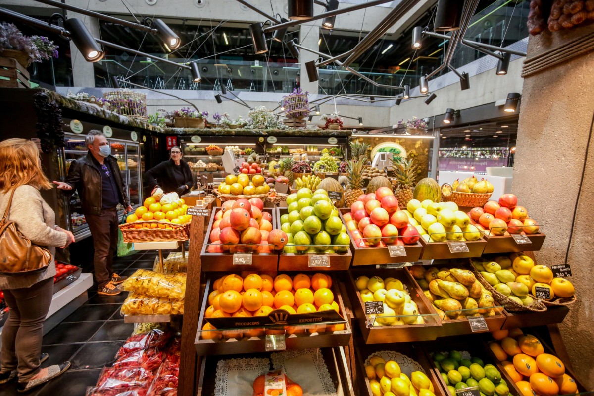 Archivo - Varios clientes hacen la compra en un puesto de fruta en el mercado de San Antón en Madrid (España)