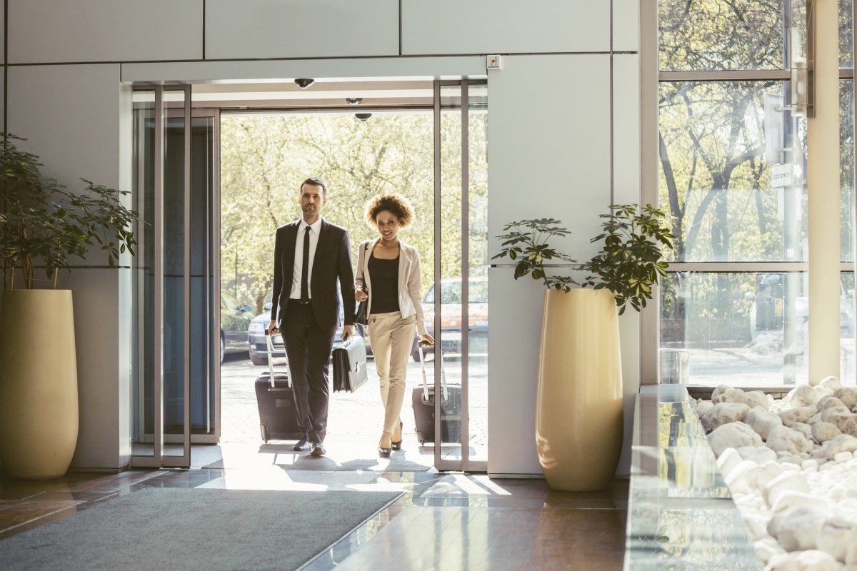 Archivo - Viajeros de negocios entrando en un hotel con sus maletas.