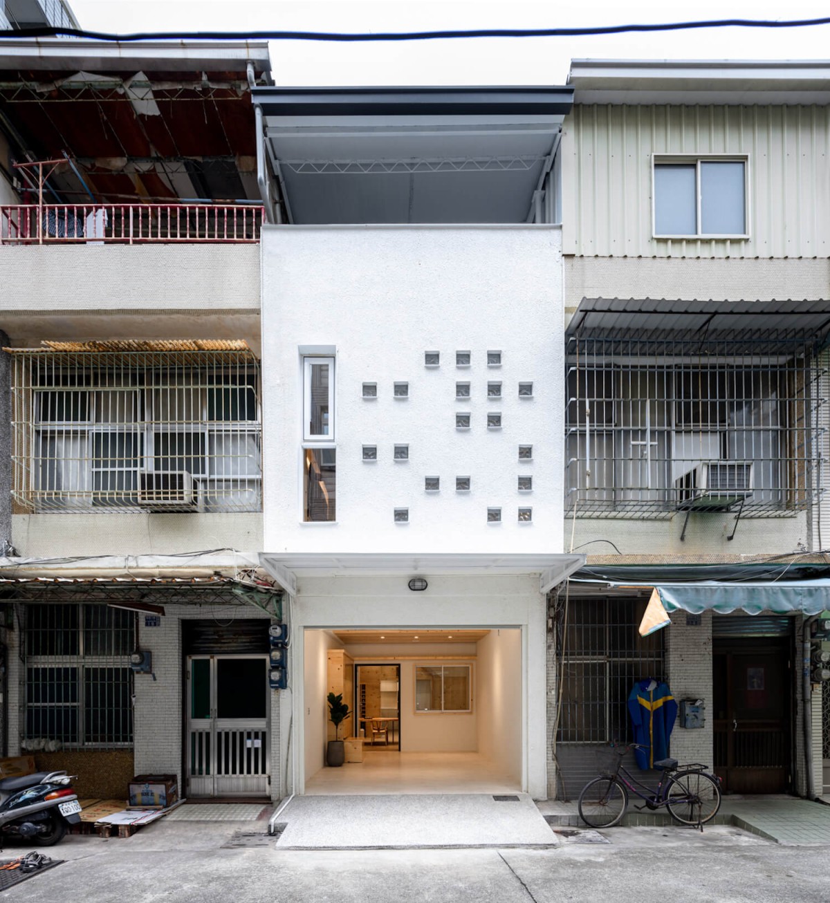 La fachada con revestimiento blanco y ventanas salpicadas son el elemento más característico de la House OO