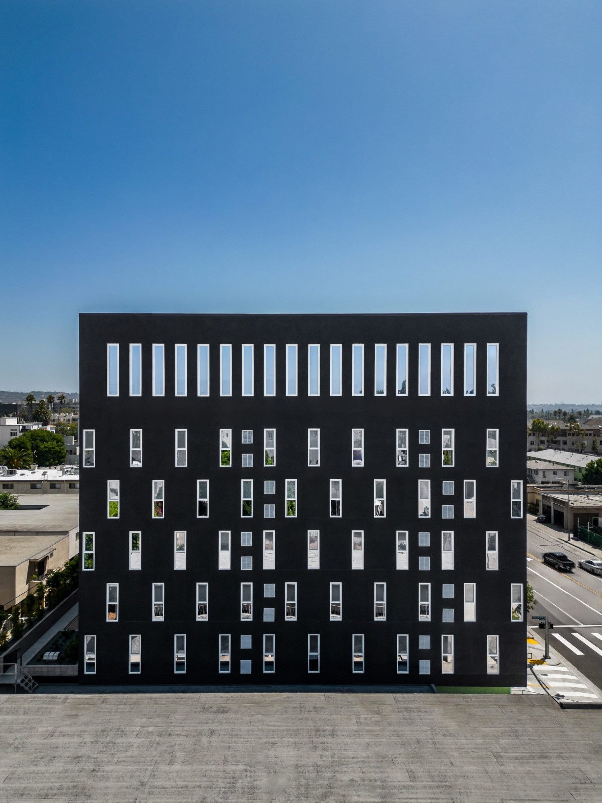 Las ventanas se distribuyen por la fachada a través de un patrón escalonado, desplazado y repetido en los niveles intermedios del edificio.