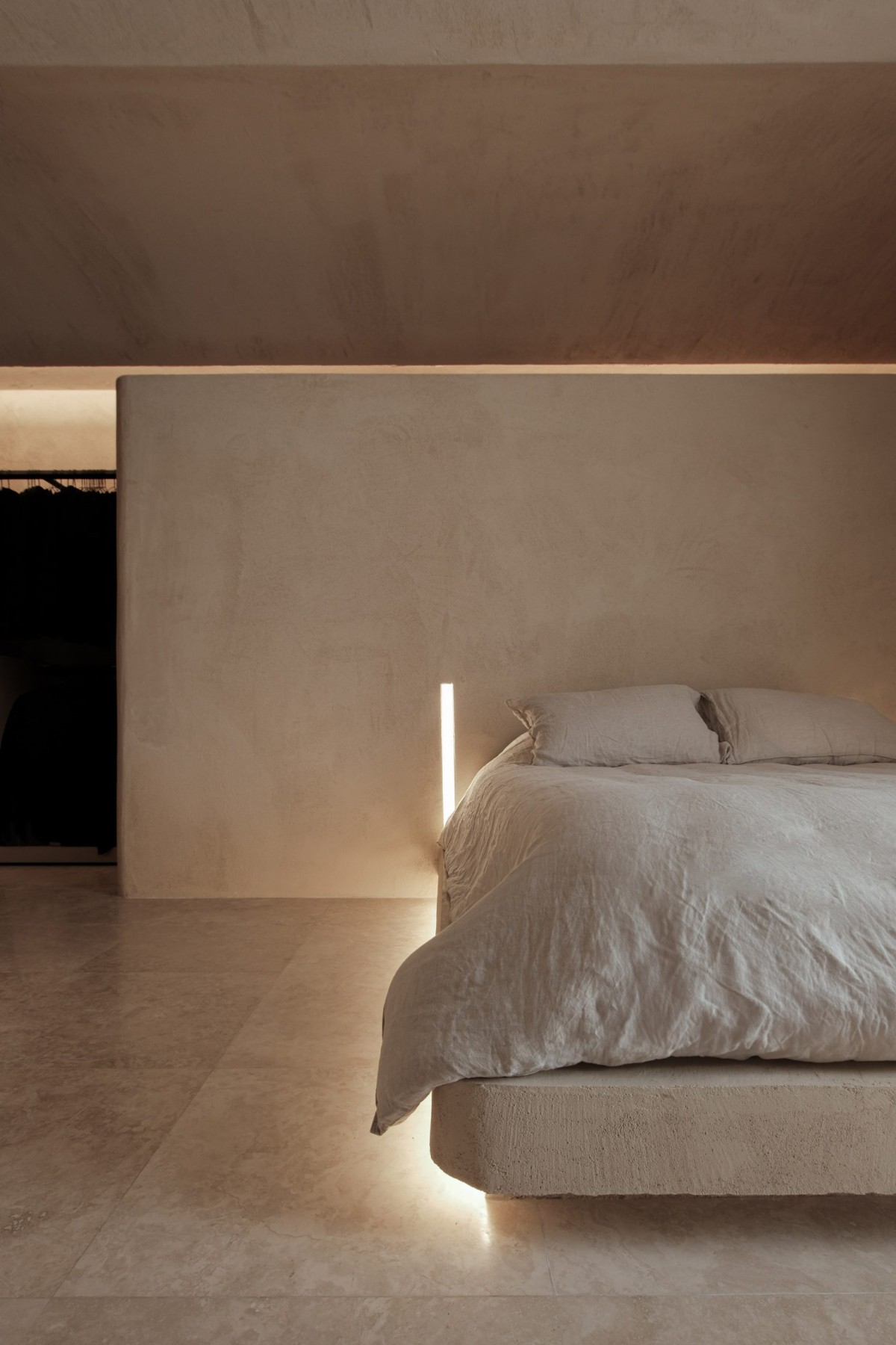 El dormitorio principal también está acabado con los tonos terrosos de la fachada. Un muro separa el cabezal de la cama con el espacio de cambiador.