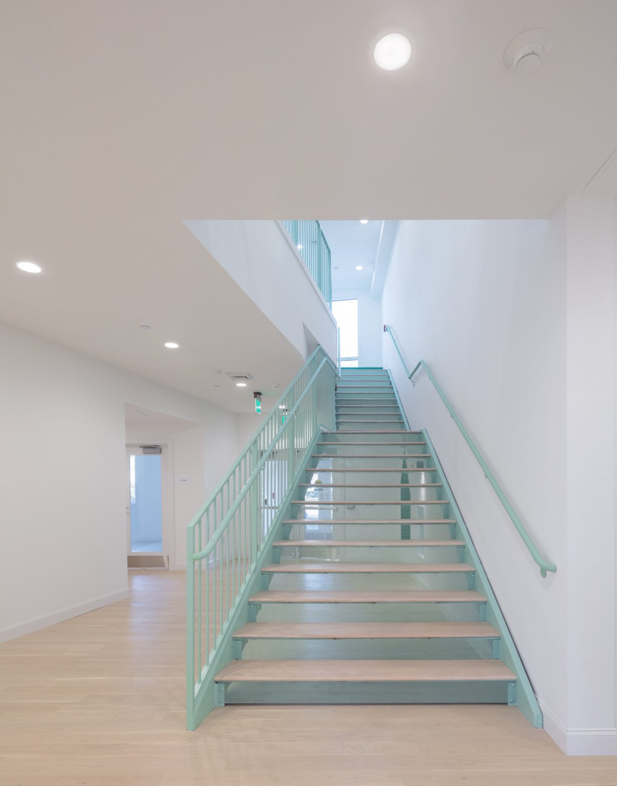 Los espacios interiores se distribuyen en altura mediante escaleras estéticamente sencillas y elegantes de color verde y peldaños de madera.