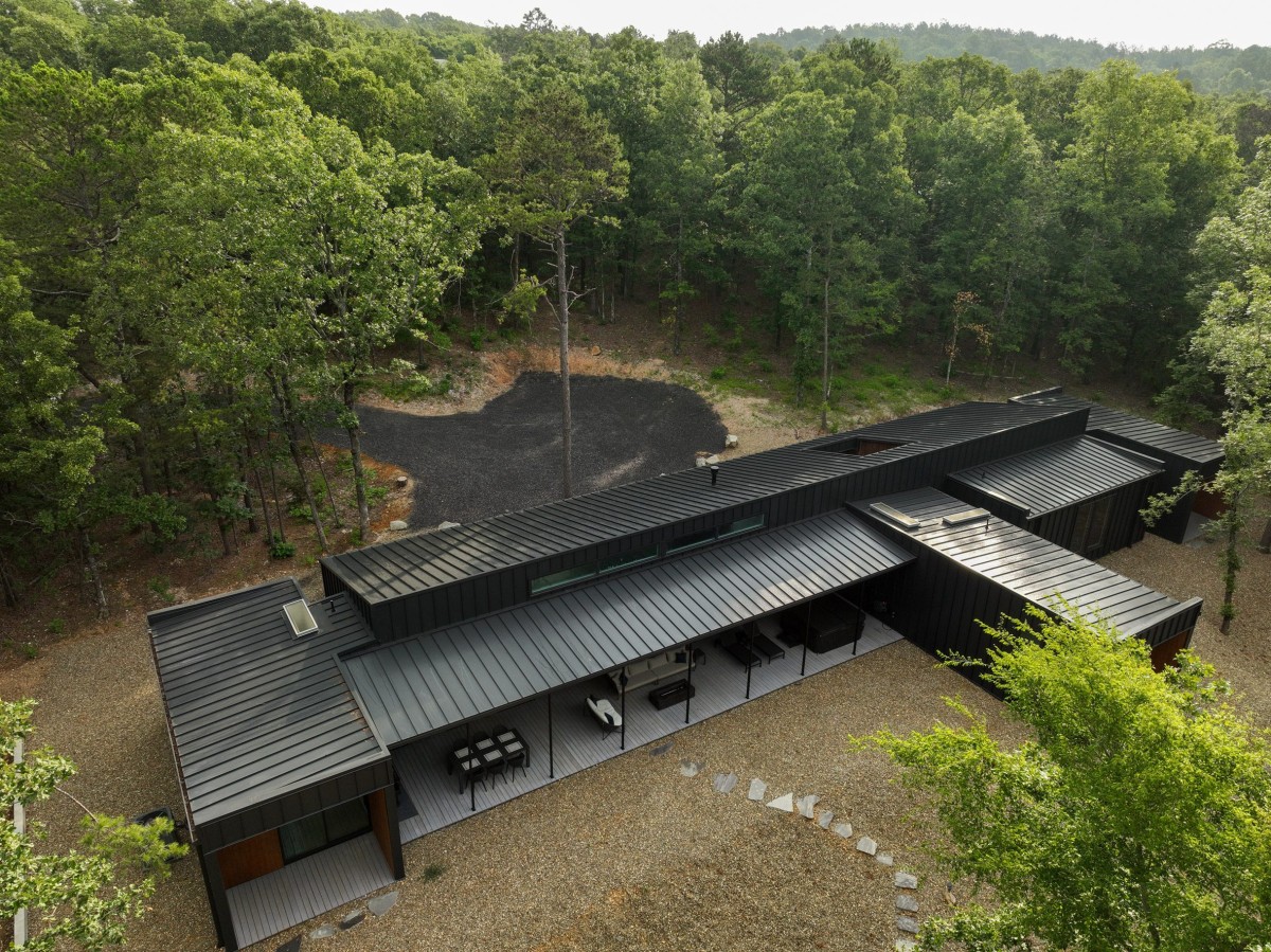 El exterior pinta de oscura por el revestimiento de metal negro en las paredes y tejados, así como por el uso de madera de cumarú brasileña de tonos cálidos.
