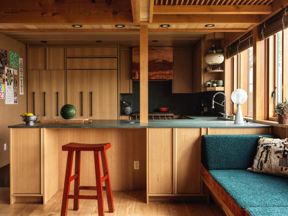 La cocina cuenta con una encimera de esteatita verde oscuro que contrasta con las tonalidades de madera de los armarios.