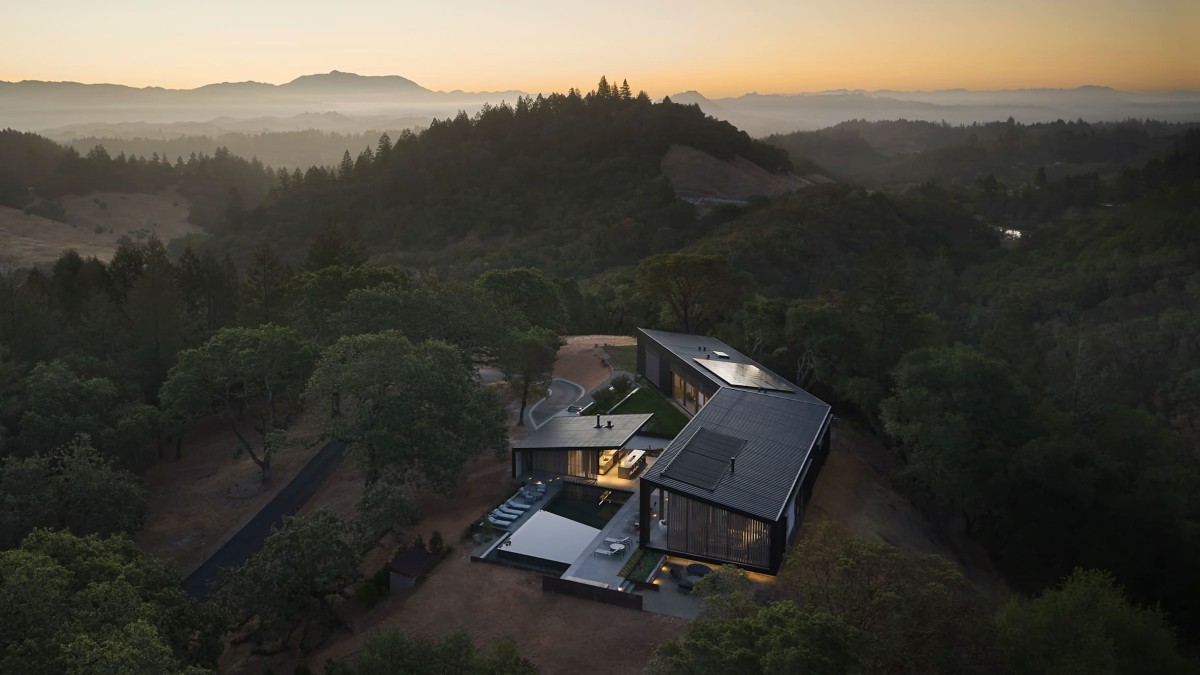 La vivienda se asienta en lo alto de una colina aislada cuyo acceso implica recorrer un largo y sinuoso camino de grava.