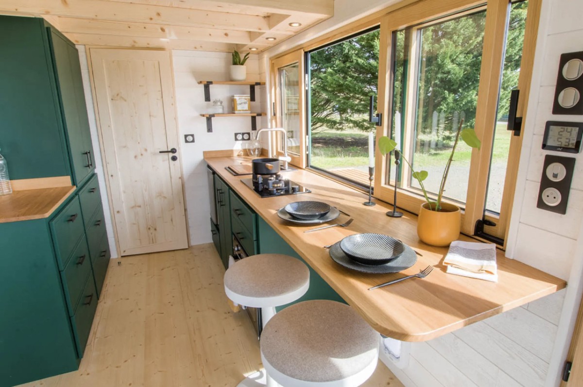 La cocina está equipada con una barra y taburetes para dos personas, un fregadero, un horno, un frigorífico pequeño y una cocina de propano con dos fuegos.