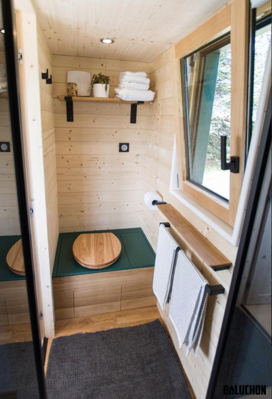 El baño compacto incluye un inodoro seco y una ducha, ofreciendo todas las comodidades necesarias en un espacio reducido.