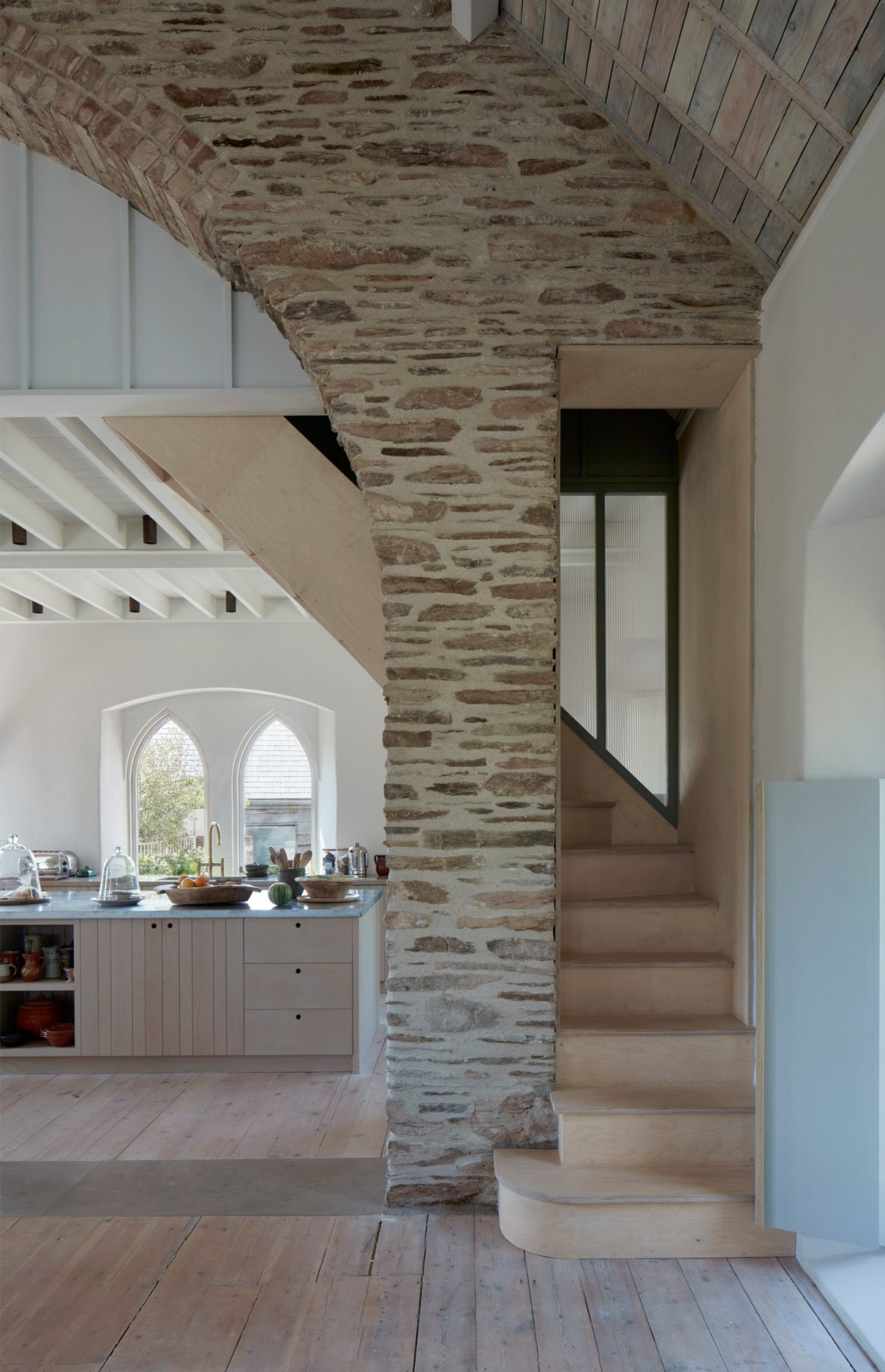 La sala de estar principal, enmarcada por un impresionante arco de piedra y vigas de madera a la vista.