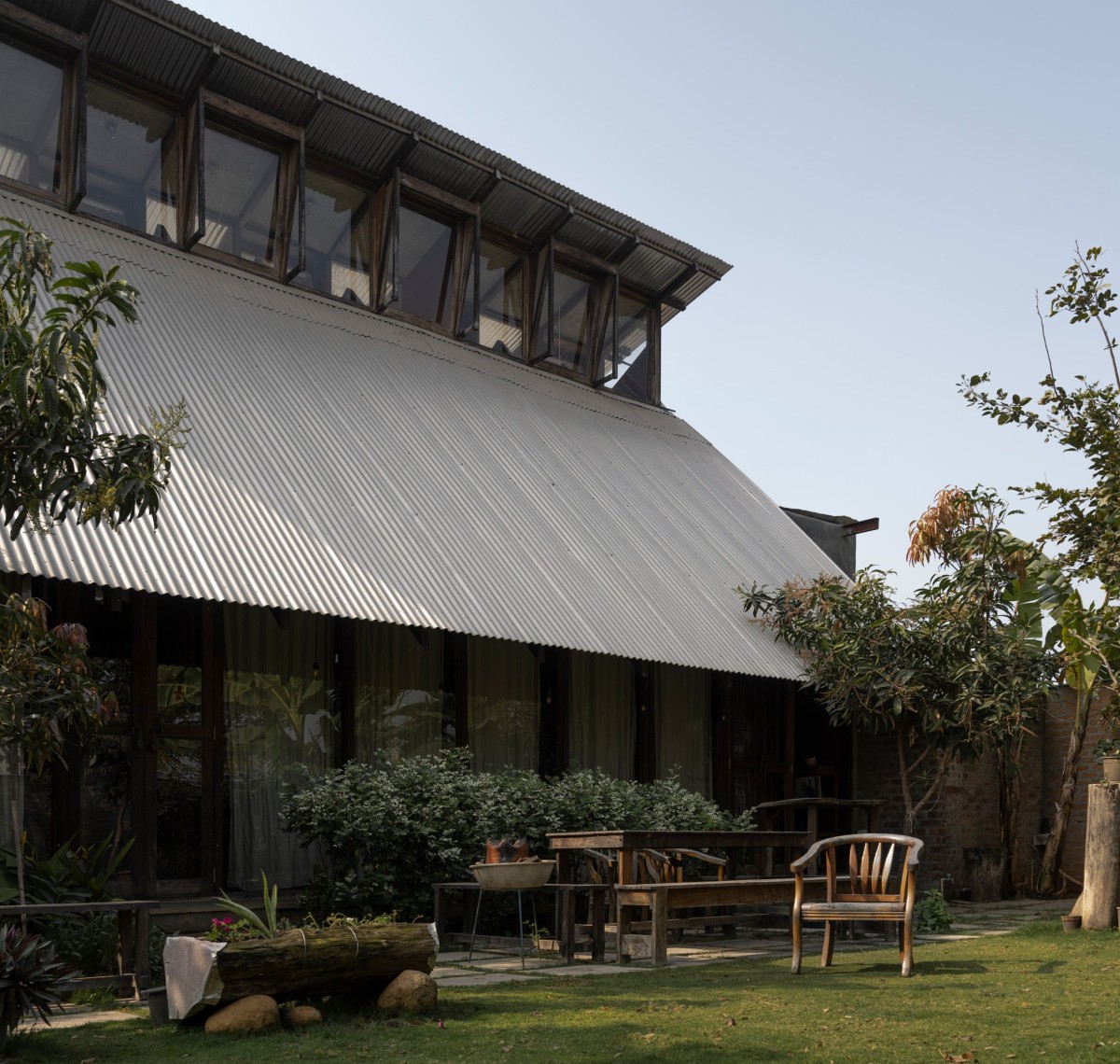 La cubierta de aluminio ondulado desciende hasta el gran jardín de la propiedad.