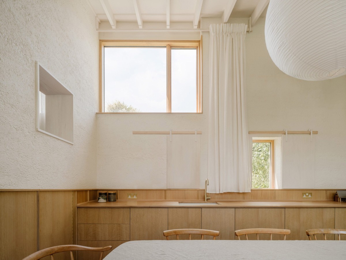 Los armarios y cajones a medida se extienden a lo largo de una pared, integrando un fregadero que facilita el almacenamiento y la preparación de alimentos. 