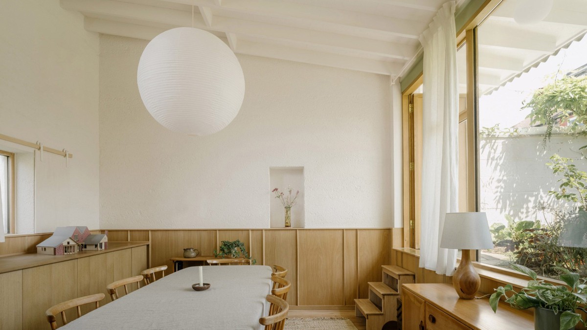 En el centro del espacio de trabajo, una larga mesa cubierta con un mantel beige sirve como área de trabajo informal.