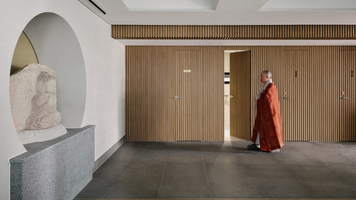 Las paredes revestidas con paneles verticales de madera ocultan las puertas a los espacios de servicio, como el almacén y los aseos.