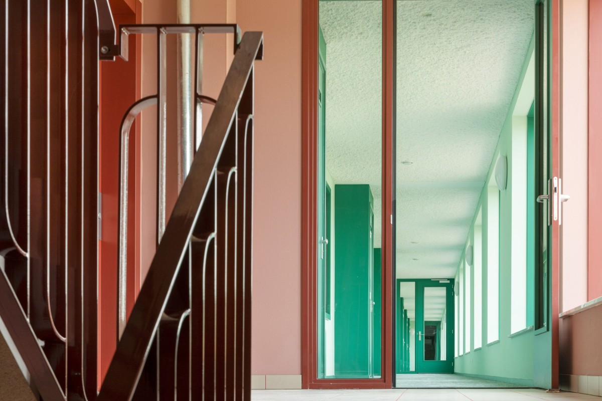 Las zonas de circulación y el pasillo de acceso están decorados en tonos verdes, rosa pálido y naranja, proporcionando un ambiente acogedor y distintivo.