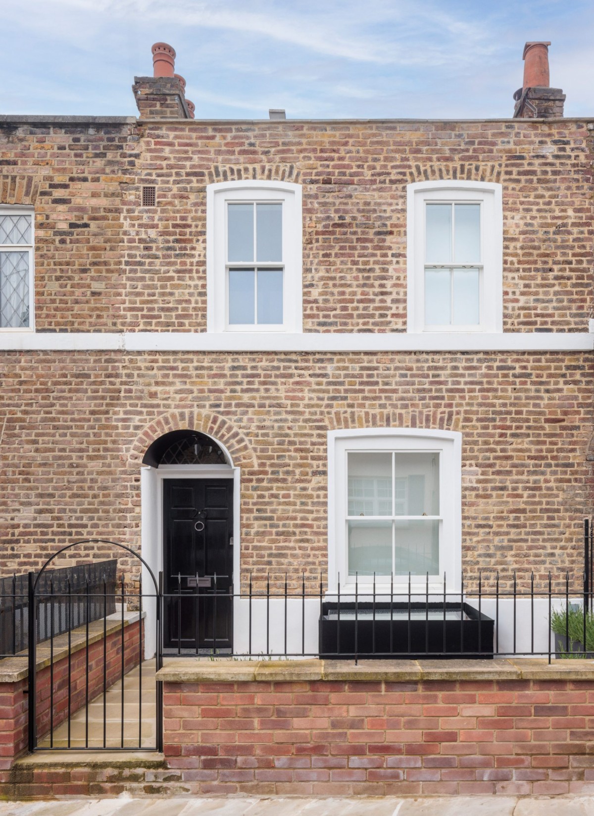 Las ventanas de PVC han sido reemplazadas por ventanas de guillotina de madera, restaurando el carácter original de la fachada.