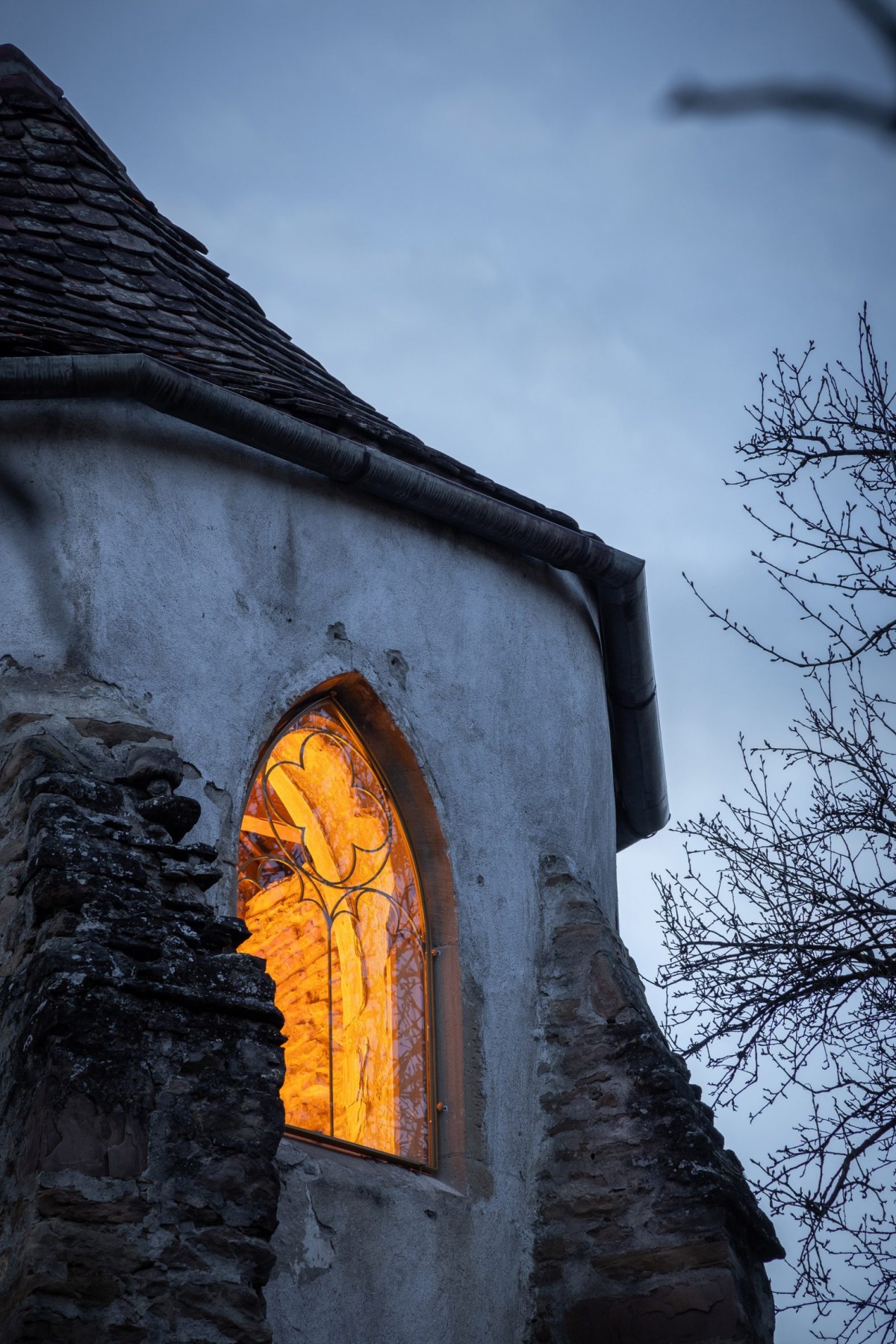 Las tres ventanas góticas del ábside han sido restauradas con marcos metálicos de perfil fino, respetando el carácter original del edificio.