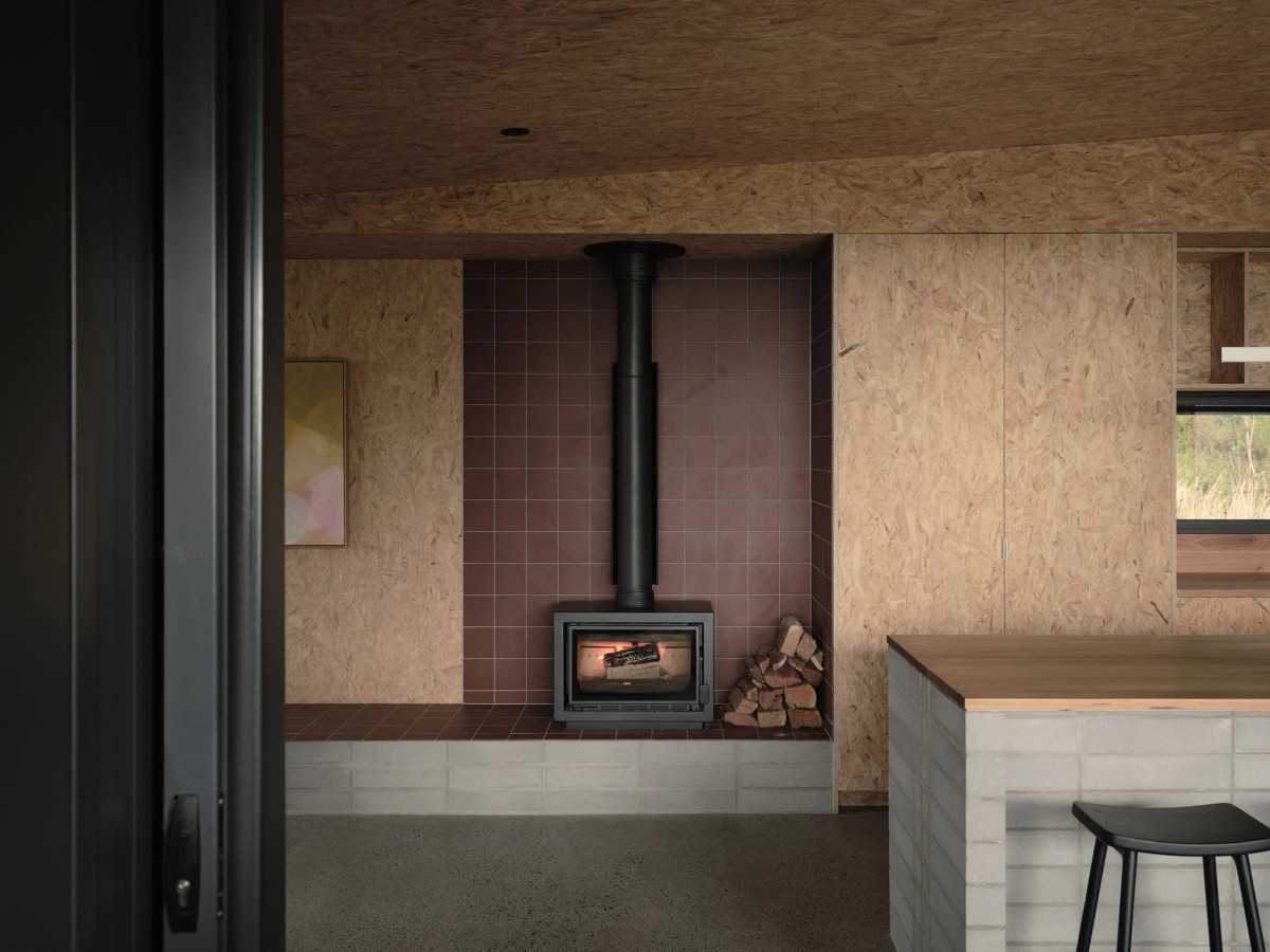 En el espacio común se encuentra una chimenea empotrada, acompañada por un banco revestido de azulejos rojos, que marca la transición hacia el salón.