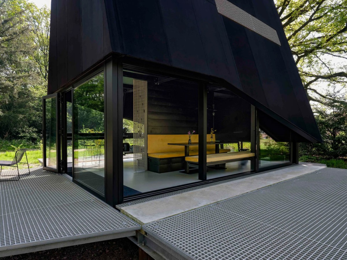 La estructura parece una figura misteriosa, con sus rejillas plegadas, como si hubiera aterrizado en medio del bosque.