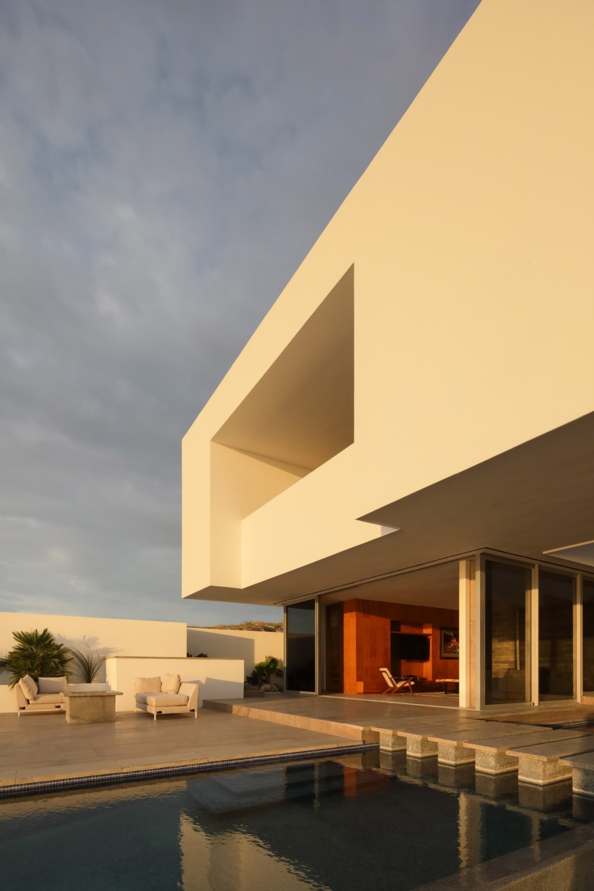 En la planta superior, un volumen sólido alberga las habitaciones y capta las brisas que llegan desde el mar y el desierto, facilitando la ventilación cruzada.