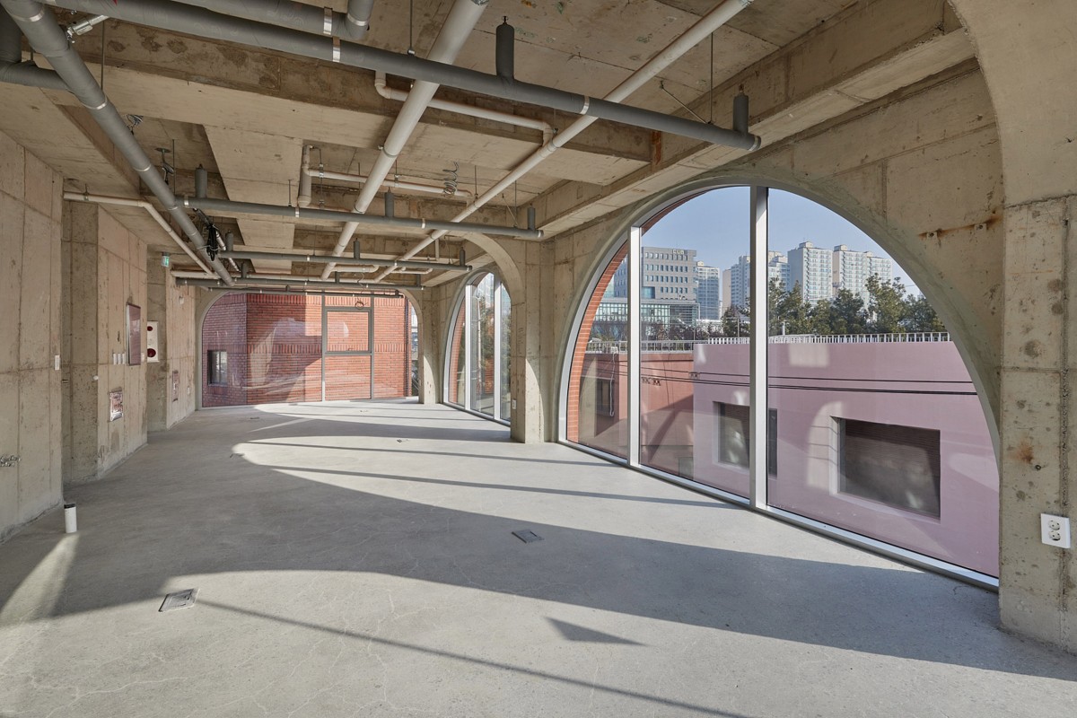 El interior de los espacios comerciales también mantiene una estética industrial, con tuberías y la estructura de hormigón a la vista.