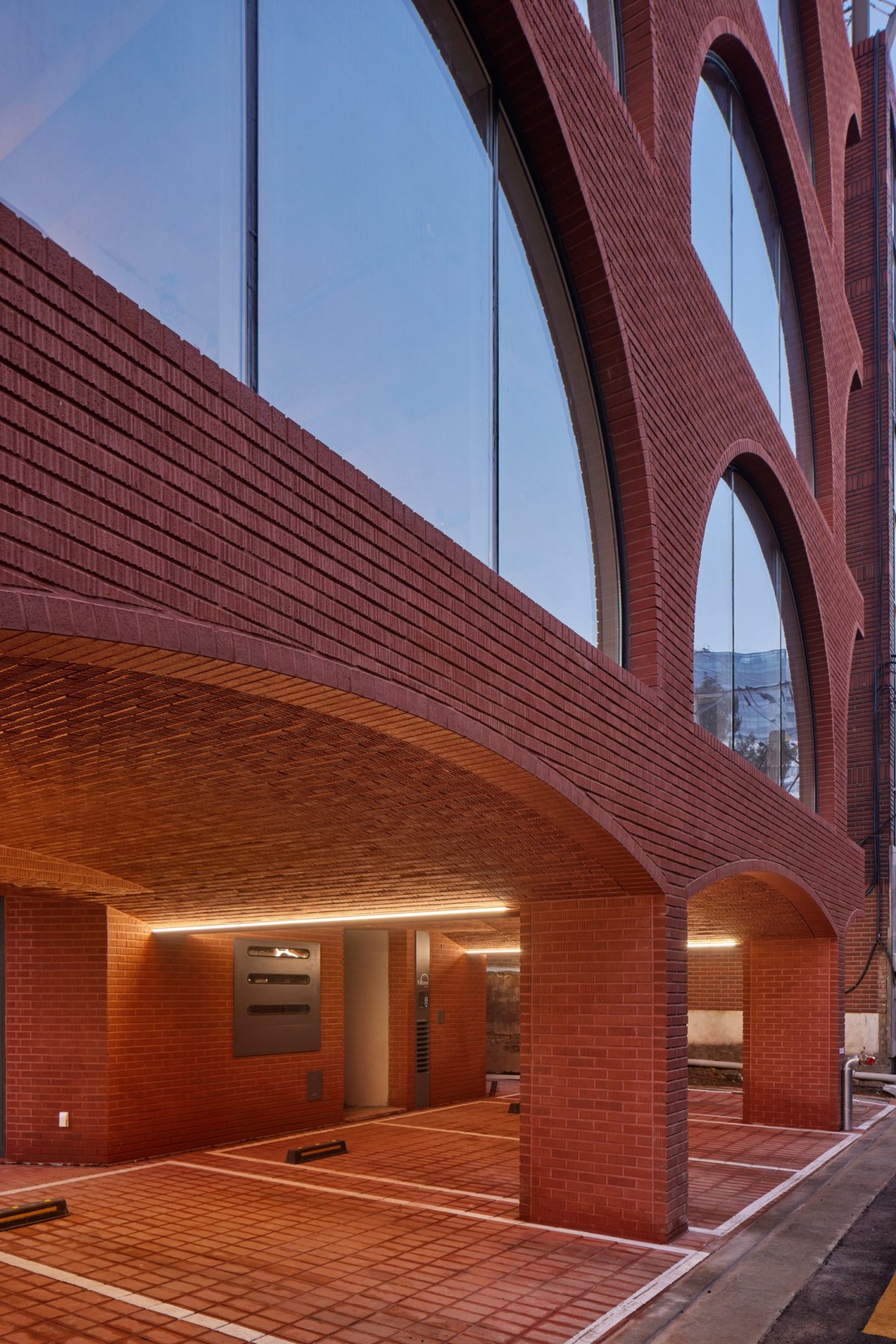 El edificio cuenta con una base elevada en pilotis de ladrillo, que se emplea para crear un espacio de aparcamiento techado. 