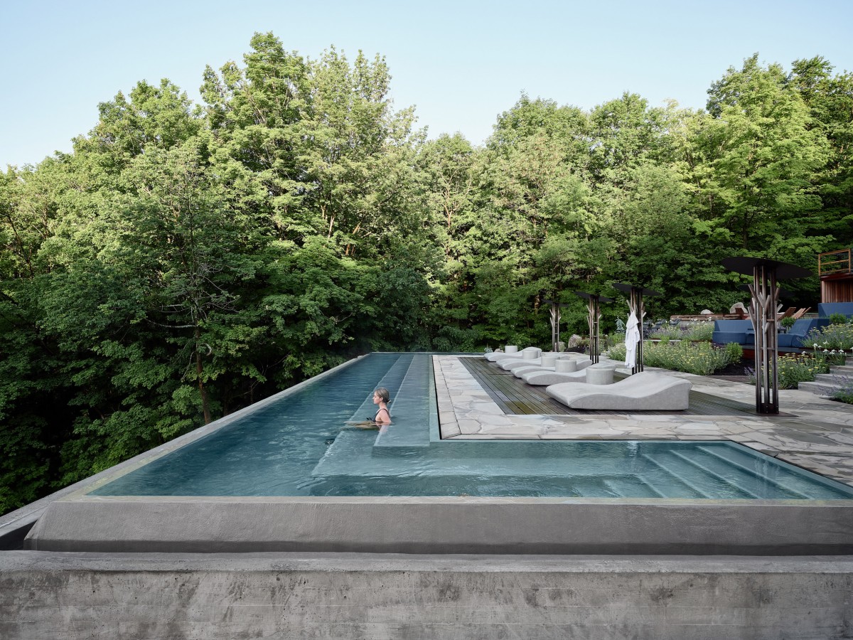 La piscina, en forma de U, se caracteriza por un banco sumergido en el agua que permite a los visitantes observar el entorno mientras se relajan.