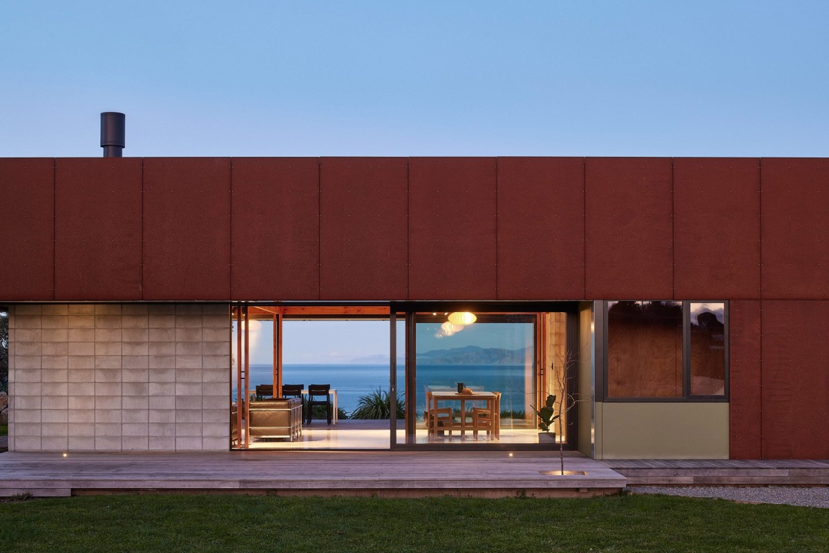 Su exterior está cubierto de un revestimiento de madera pintada en un tono rojo intenso, complementado con acero desgastado.