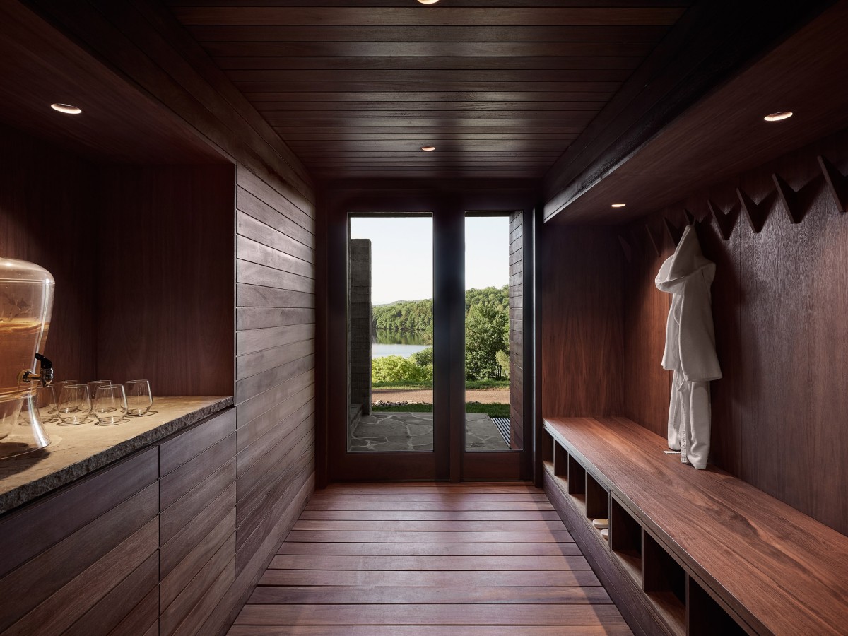 El interior de la sala de relación está revestido de madera oscura y paneles de cristal deslizantes que se abren completamente para integrar el ambiente con el exterior