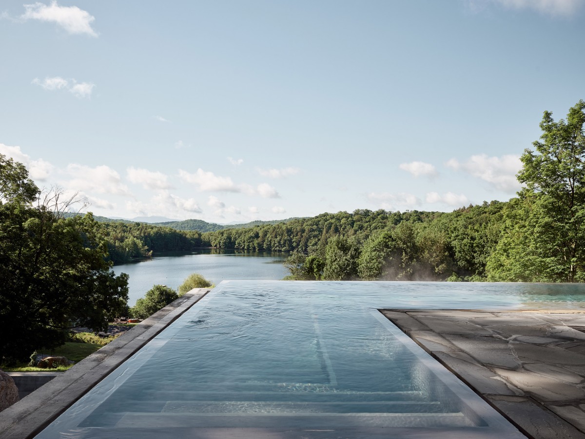 Un zócalo de hormigón sostiene una piscina infinita y una sala de relajación que ofrecen vistas panorámicas al lago Gale y los alrededores.