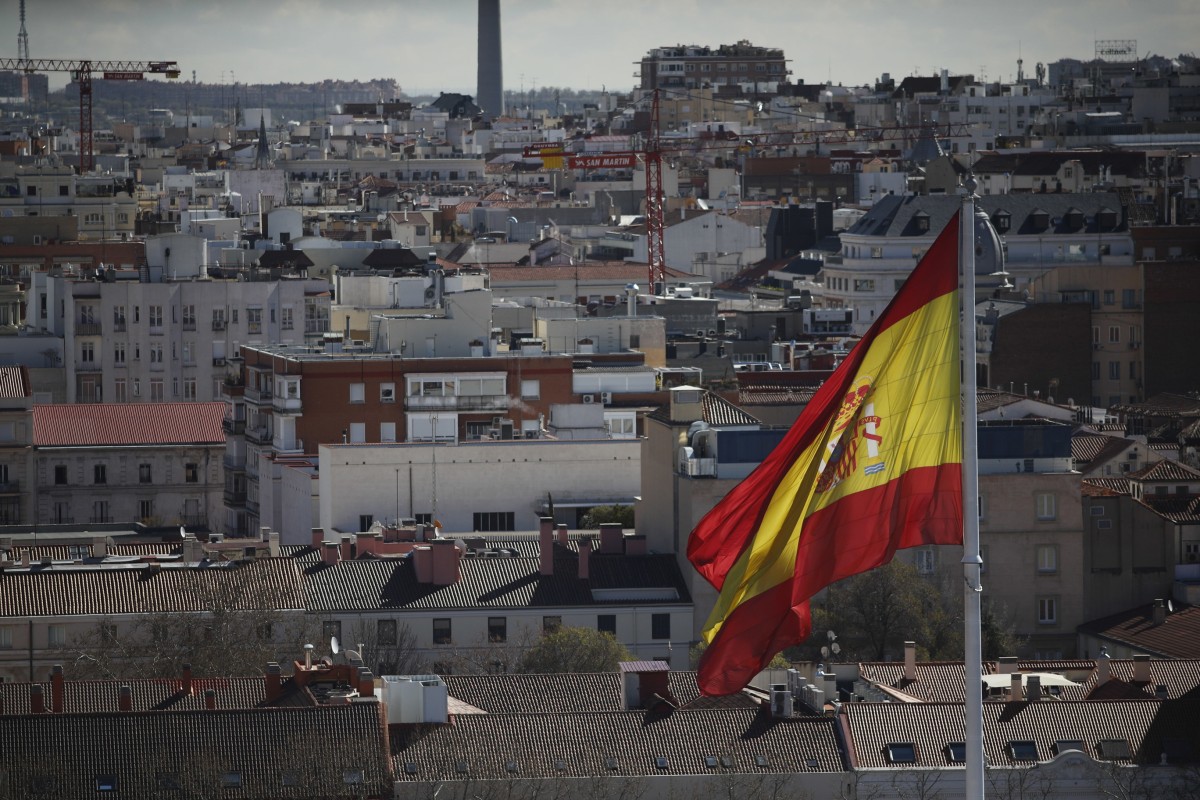 España atrajo 23.608 millones en inversión extranjera hasta septiembre, un 22% mas, con Madrid a la cabeza Archivo - La bandera de España en una visual de los tejados de Madird desde la Torre Colón.