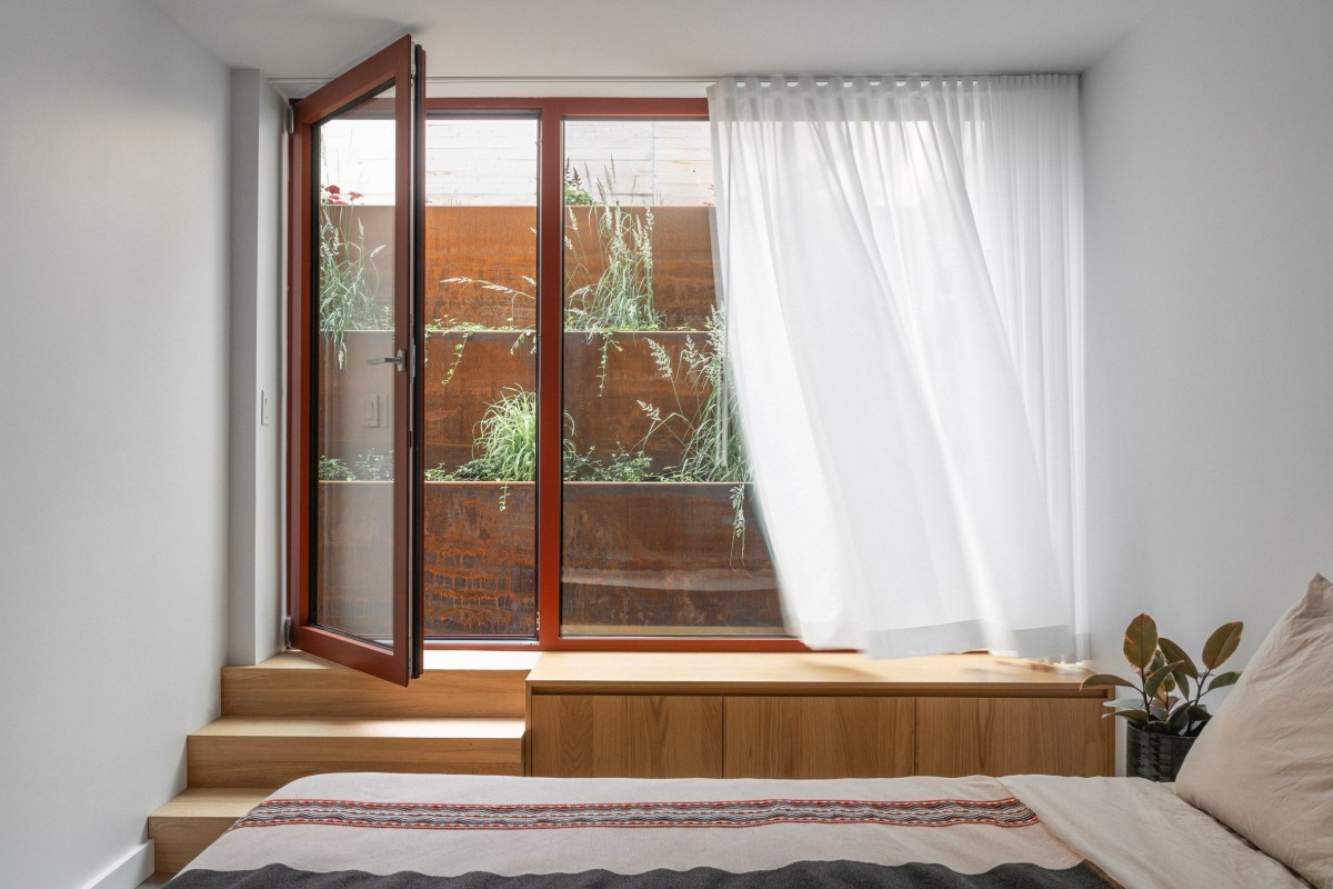 El dormitorio principal y el despacho están orientados hacia un patio de grava hundido, que cuenta con una jardinera escalonada de acero envejecido.
