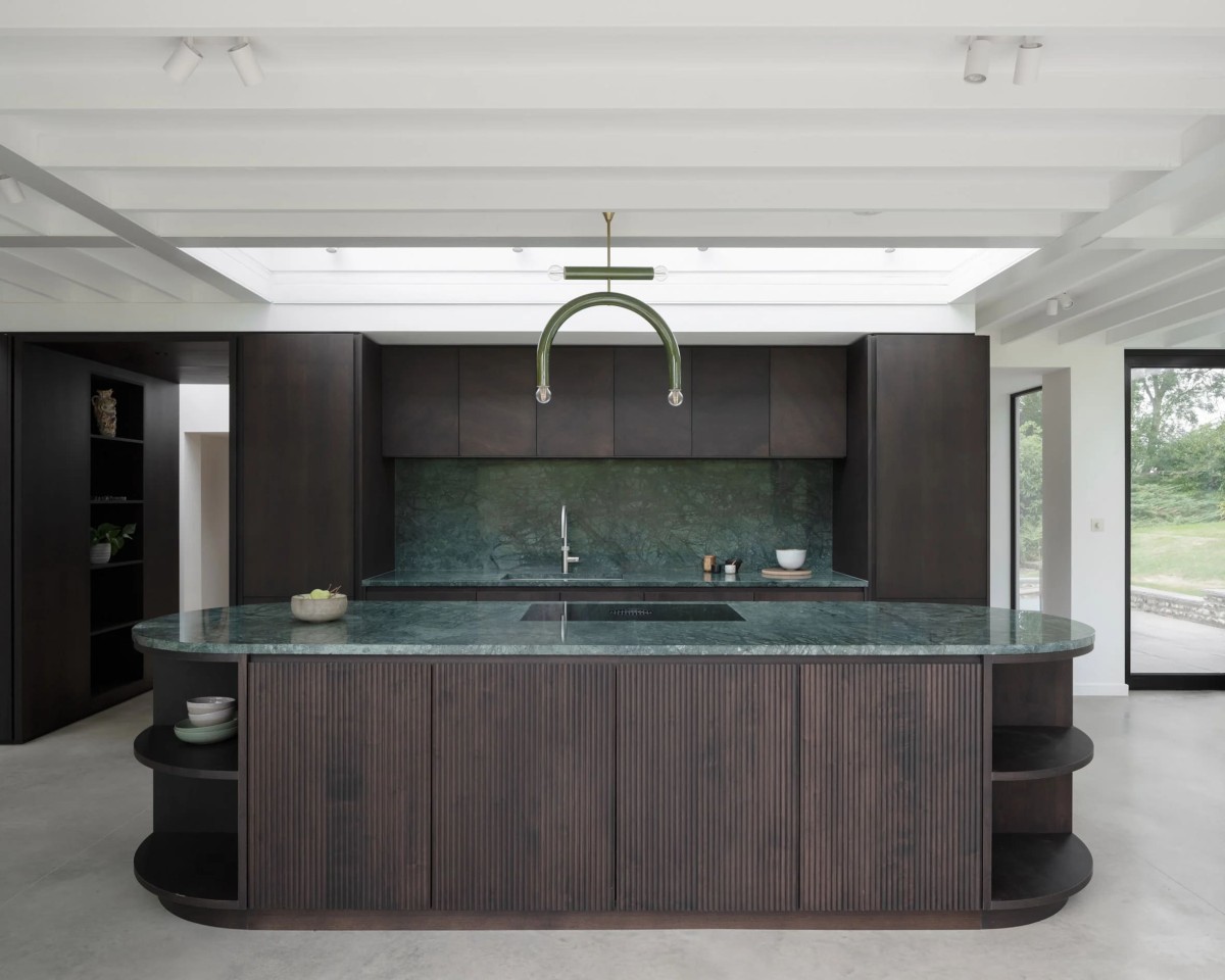 La ampliación lateral tiene una cocina y un comedor rodeados por cristal de suelo a techo.