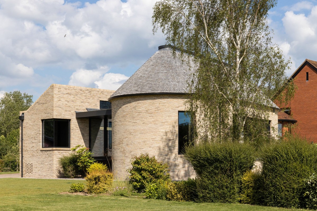 Los volúmenes de bordes curvos y ladrillo visto presentan una armonía visual con la vivienda original.