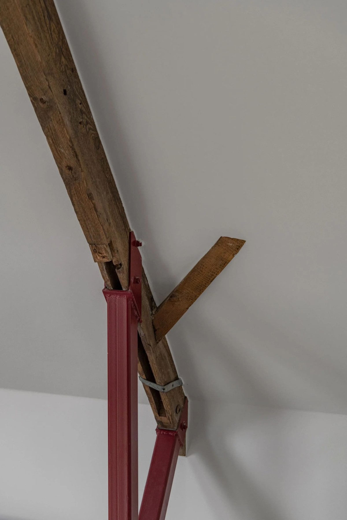 Las columnas de acero rojo sostienen la entreplanta y se apoyan directamente sobre las vigas de la estructura original de madera, reforzándola y garantizando su estabilidad.