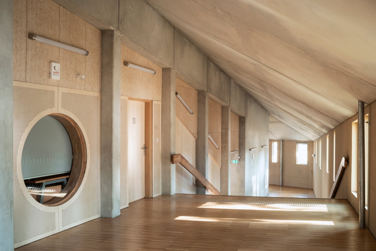 El pasillo de la escuela serpentea a su alrededor como una segunda protección de las aulas.