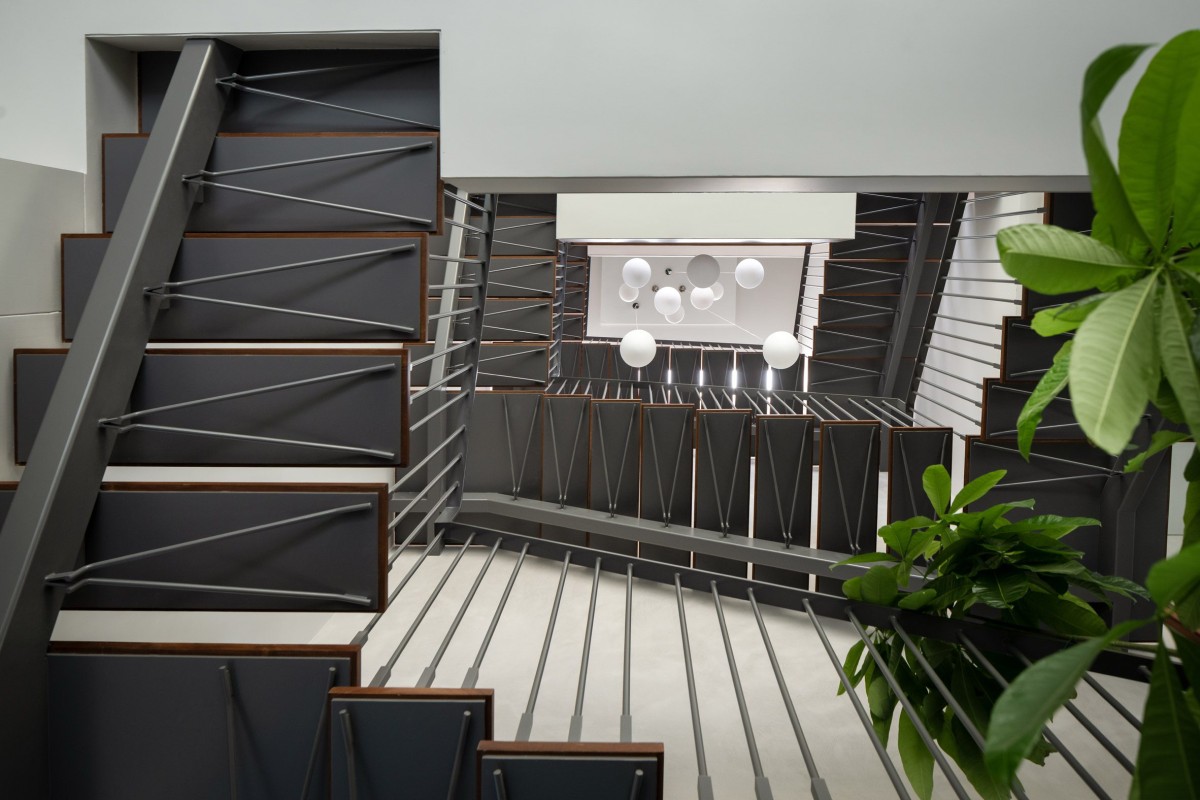 Una elegante escalera de metal y madera conecta las tres plantas de la casa.