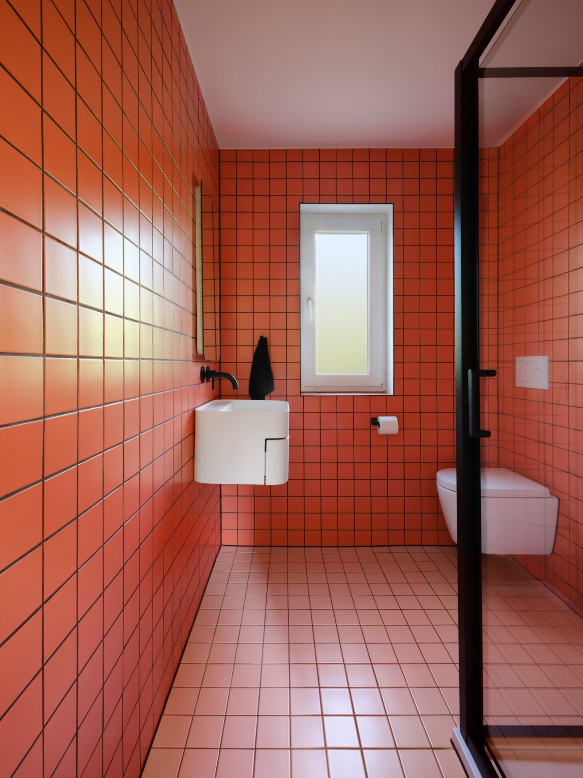 En contraste a las tonalidades pastel de la casa, está el baño, con unos azulejos rojos brillantes.