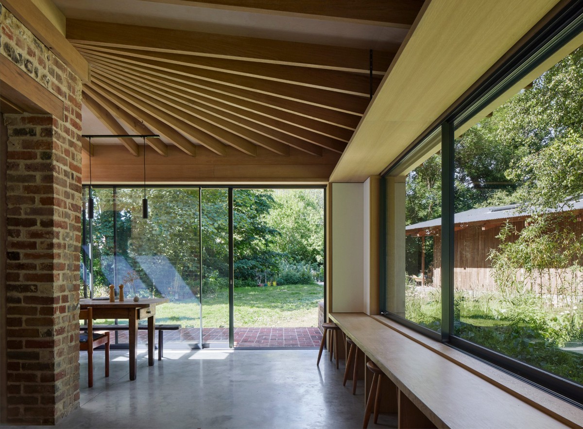 La ampliación se abre al paisaje a través de espacios acristalados con estructura de madera.