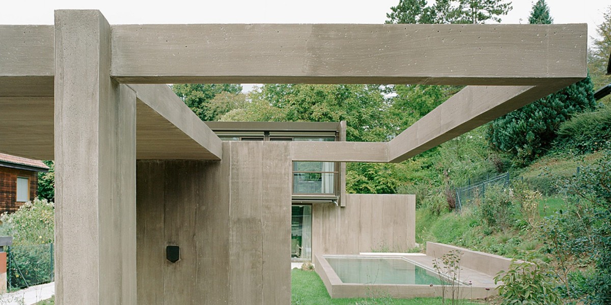 Una pequeña piscina y una terraza cubierta por una pérgola de hormigón prolongan el edificio hacia el paisaje.