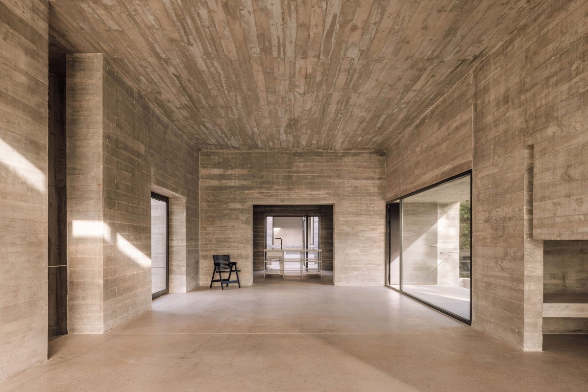 Las grandes ventanas y el hormigón visto marcado con tablas ofrece una textura tanto en el interior como en el exterior