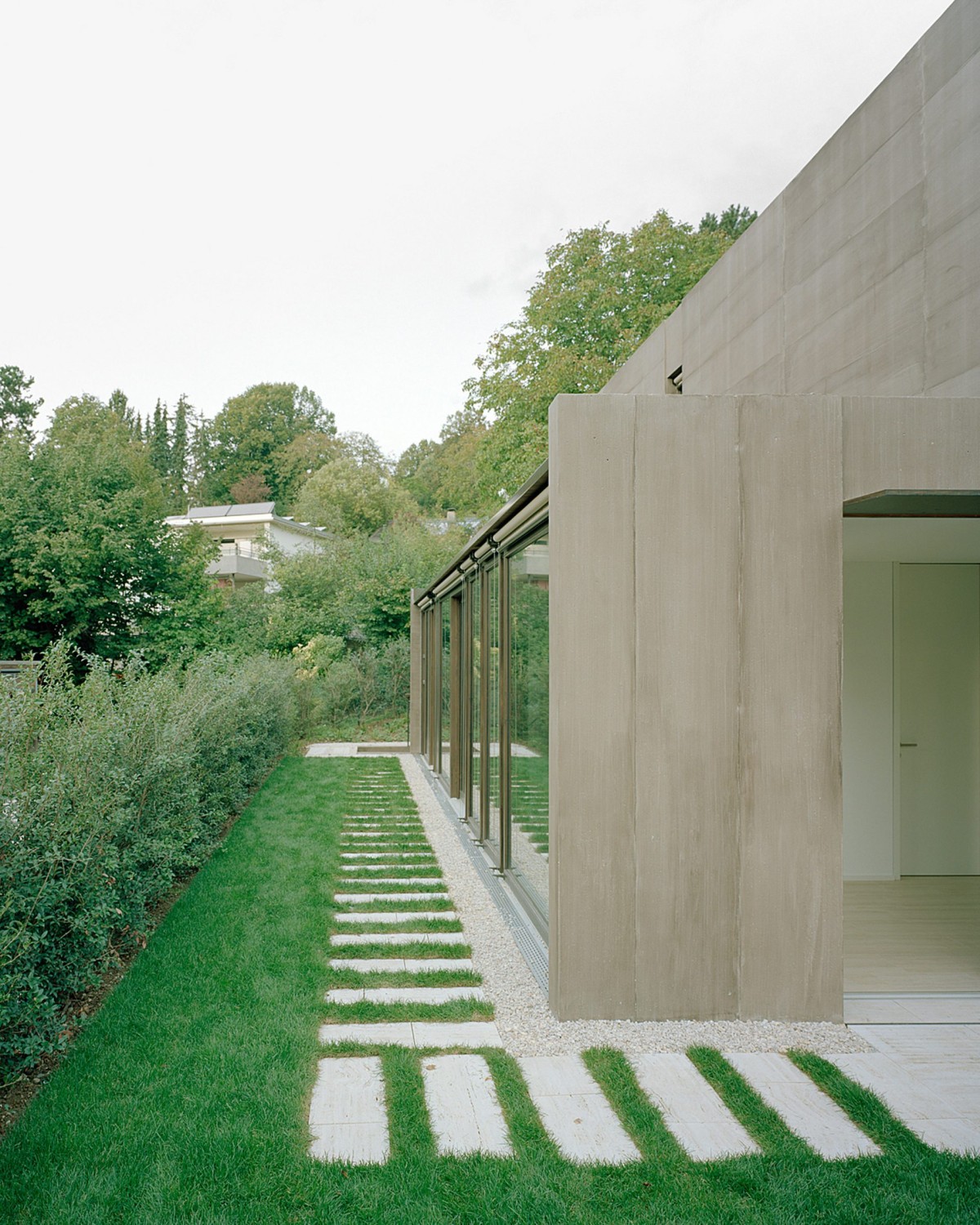 Las paredes acristaladas se abren a los jardines circundantes y dialogan con los muros de hormigón.