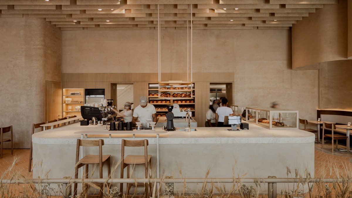 La panadería se articula alrededor de un mostrador en forma de U construido con tierra compactada, una técnica ancestral reinterpretada con elegancia contemporánea.