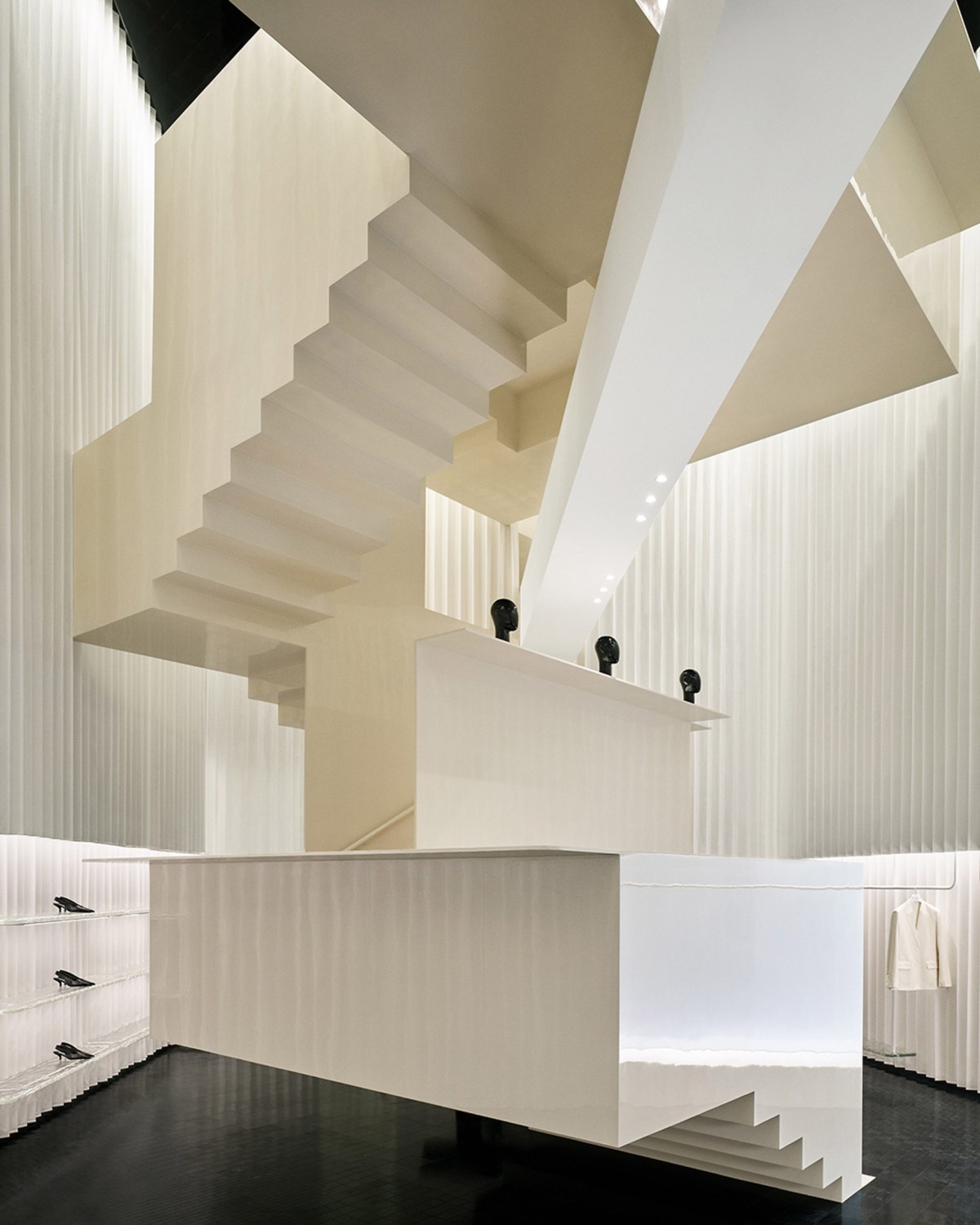 La escalera actúa como una pieza escultórica central, transformando un espacio comercial en una galería de arte contemporáneo.