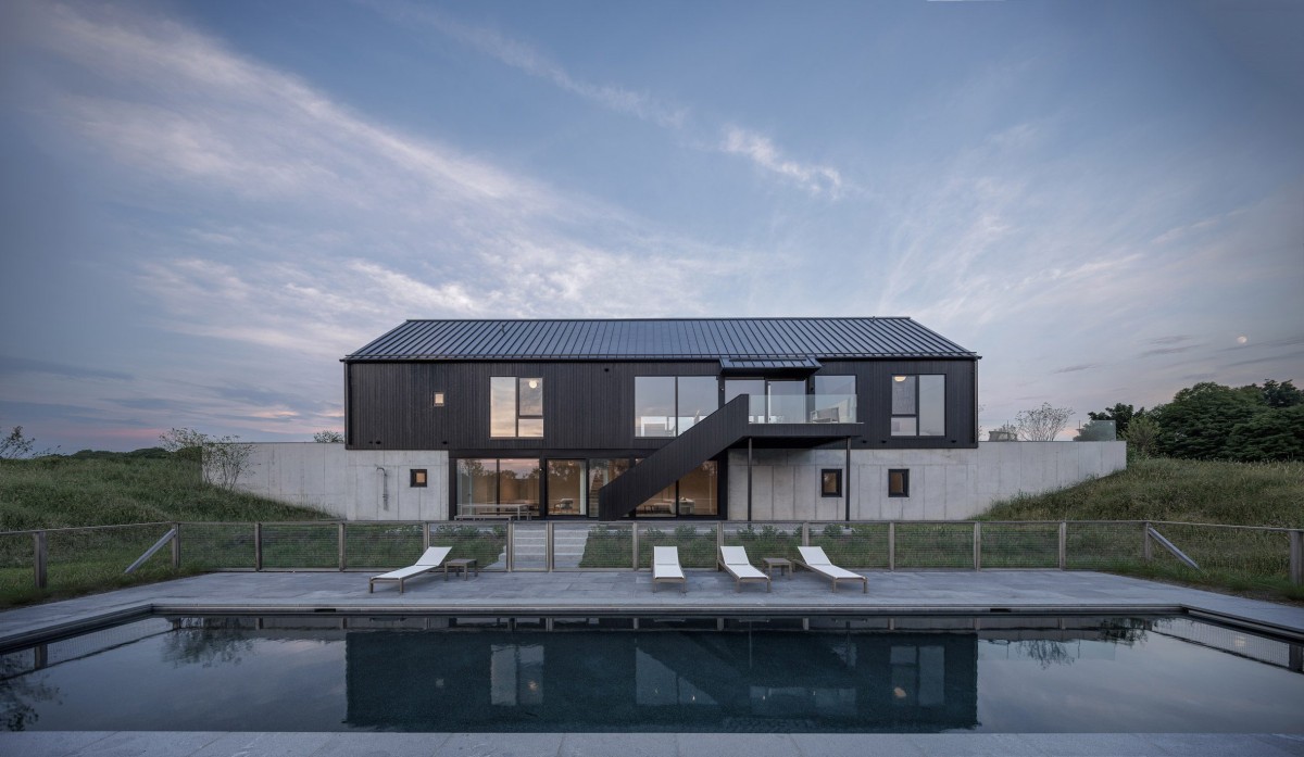 La estructura principal, de dos plantas, se integra con el terreno inclinado mediante un muro de contención de hormigón.